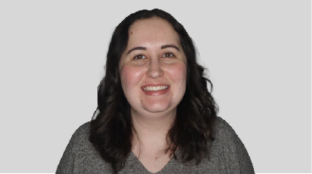 Professional headshot of a smiling woman with dark hair on a light background